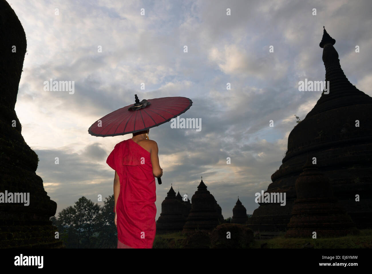 Mönch mit roten Regenschirm mit Andaw-Thein Tempel, Mrauk U, Rakhine State in Myanmar Stockfoto