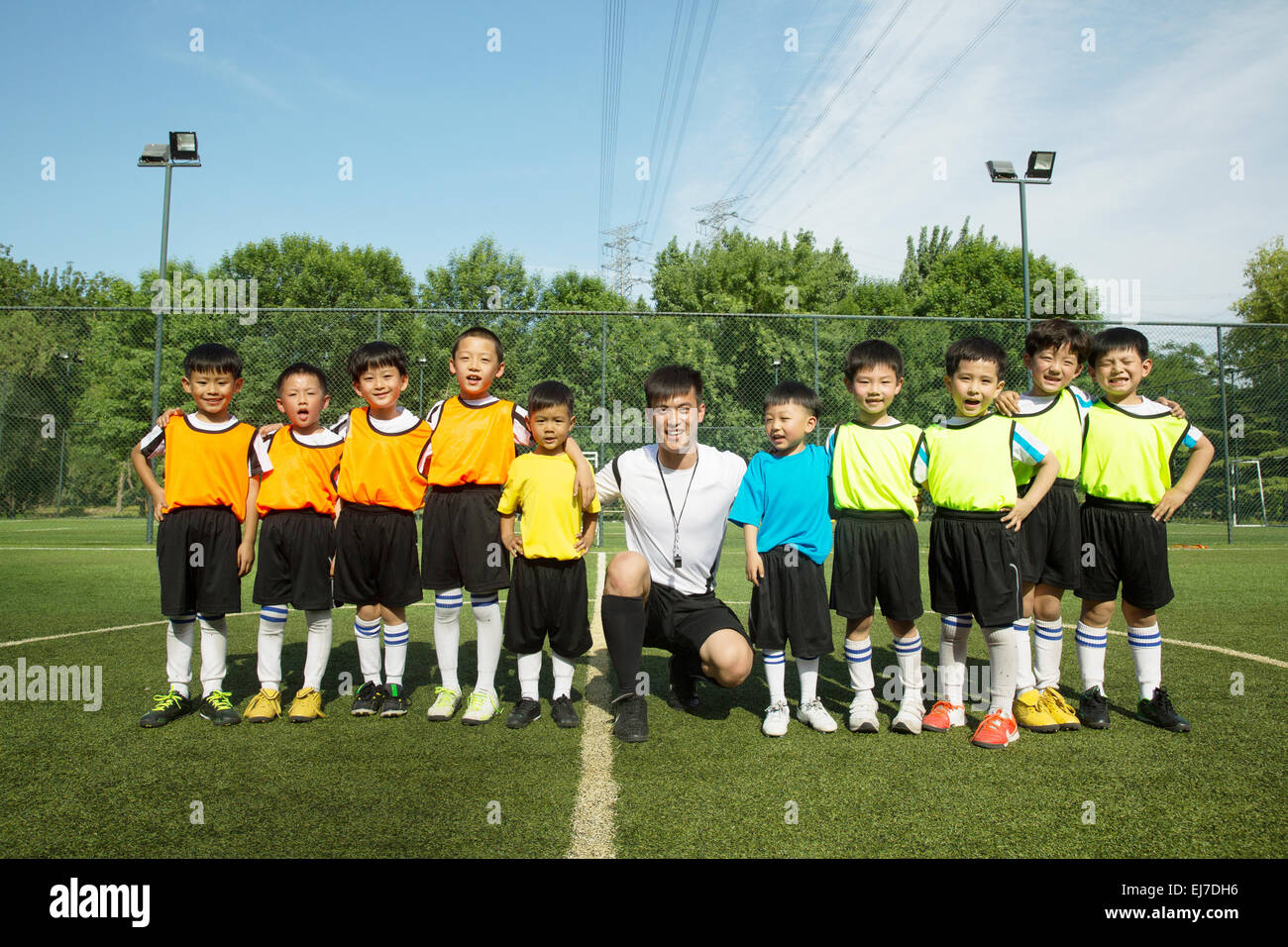 Der Fußball-Trainer und die Jungs stehen in einer Reihe in dem Fußballplatz Stockfoto