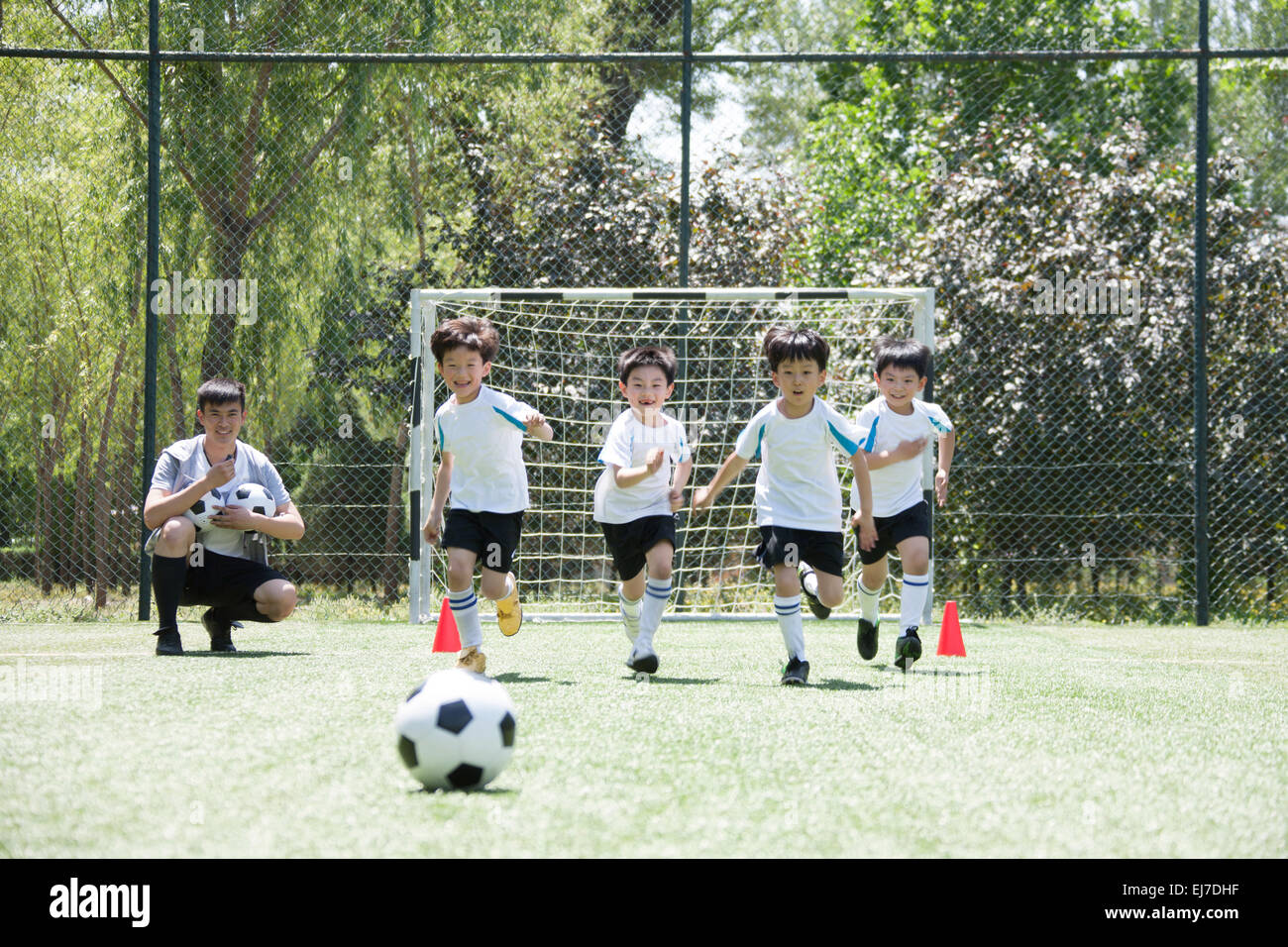 Der Trainer mit den Jungs Fußball spielen in dem Fußballplatz Stockfoto