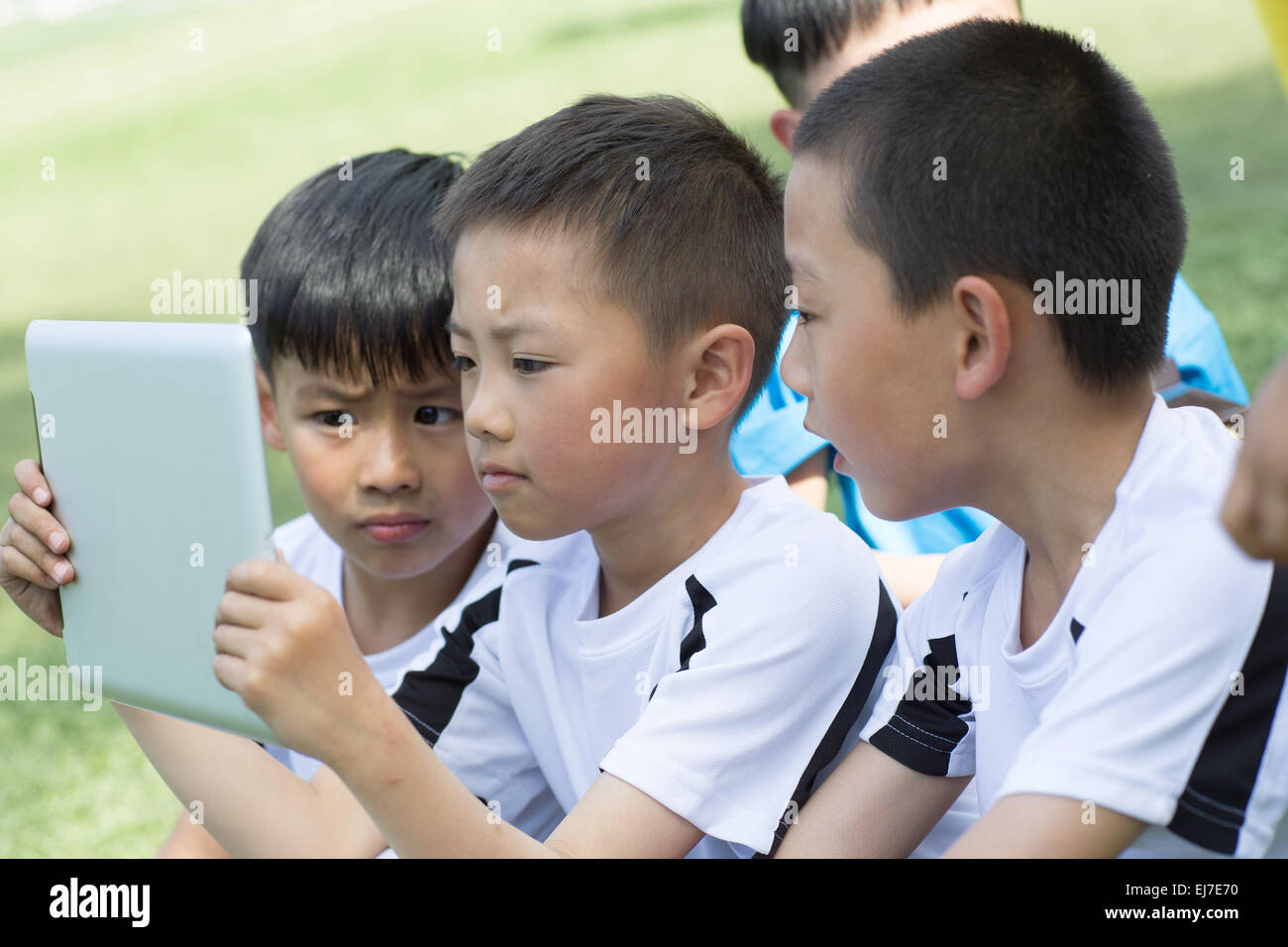 Die Kinder nahmen den Tablet-Computer mit Video auf dem Fußballplatz Stockfoto