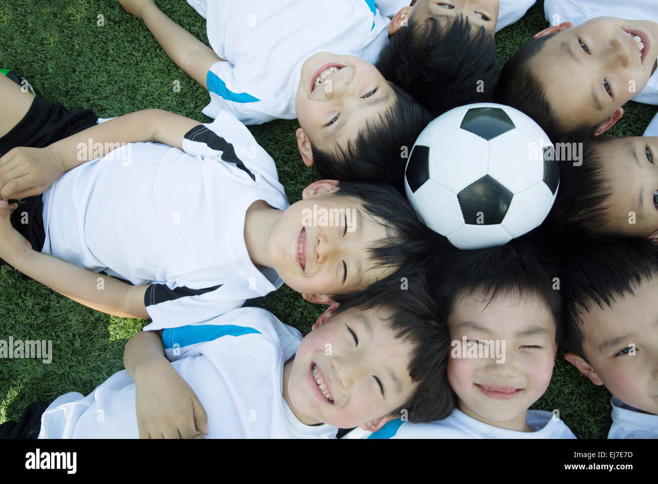 Die Kinder versammelten sich um eine Runde Lüge auf dem Fußballplatz zu bilden Stockfoto
