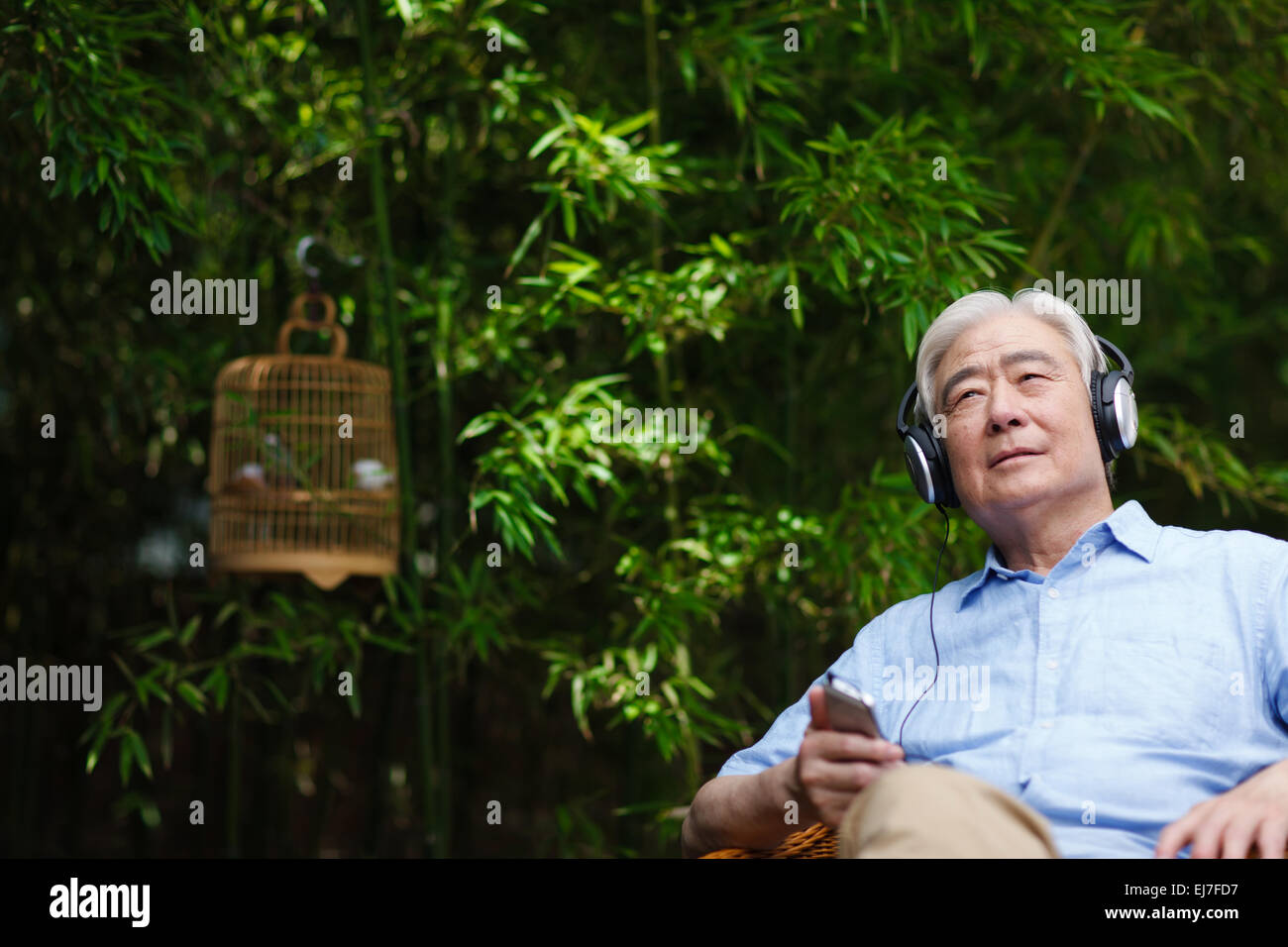 Ein Alter Mann saß auf dem Stuhl mit Kopfhörern Stockfotografie - Alamy