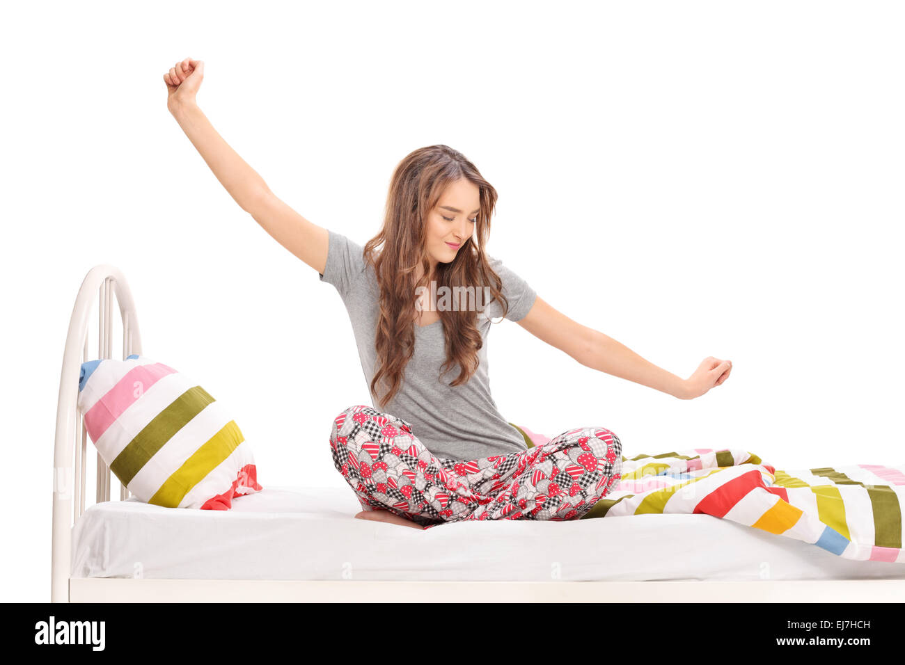 Schöne Frau am Morgen aufwachen und stretching sitzen auf einem Bett isoliert auf weißem Hintergrund Stockfoto