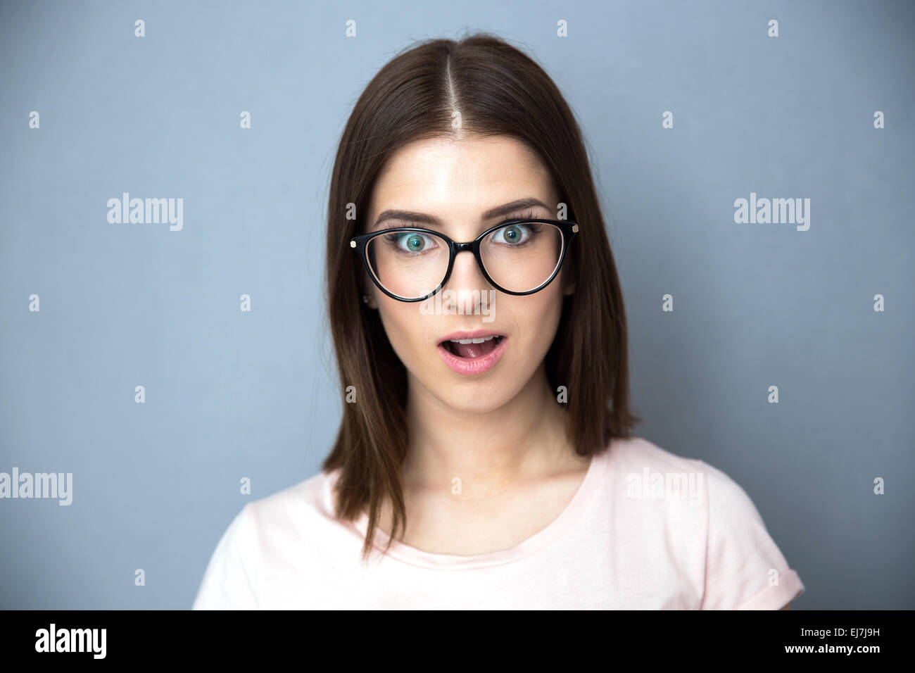 Überrascht, junge Frau in Gläsern auf grauem Hintergrund Stockfoto