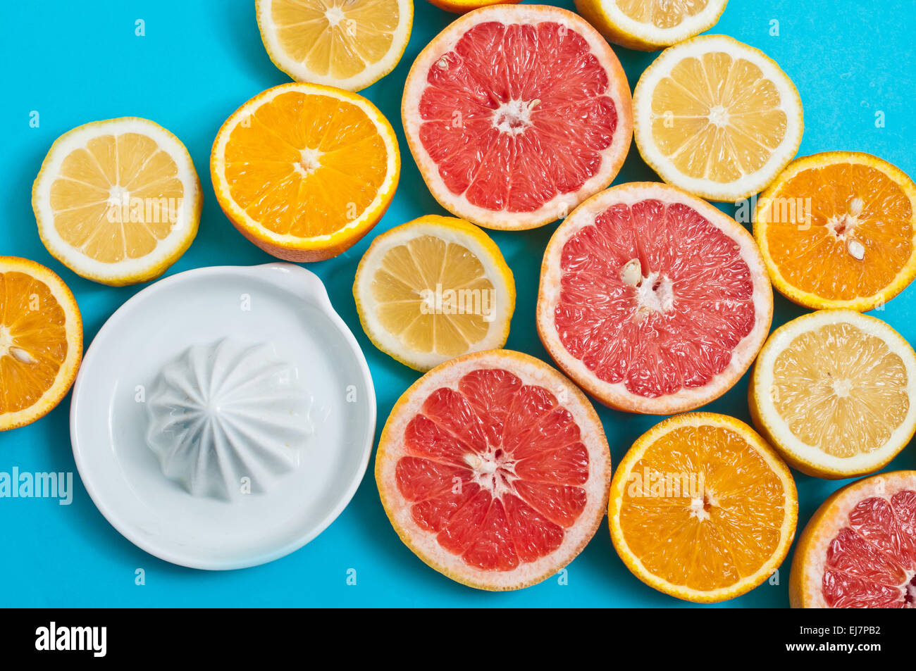 Grapefruit und Orangen und eine Saftpresse auf blauem Hintergrund Stockfoto