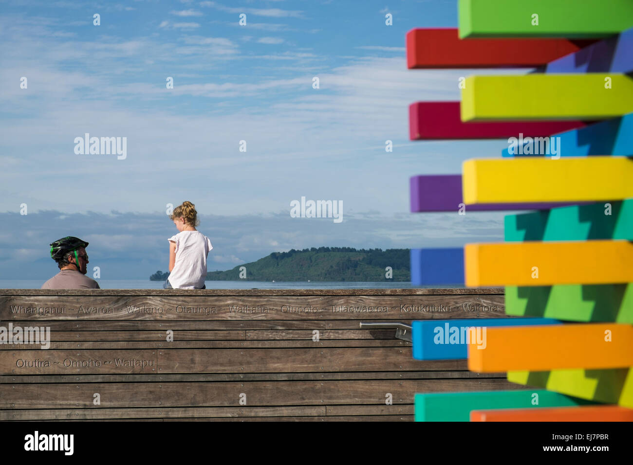 Mann mit Kindern tragen Schutzhelme Zyklus entlang der Gehweg neben Lake Taupo, Neuseeland. Stockfoto