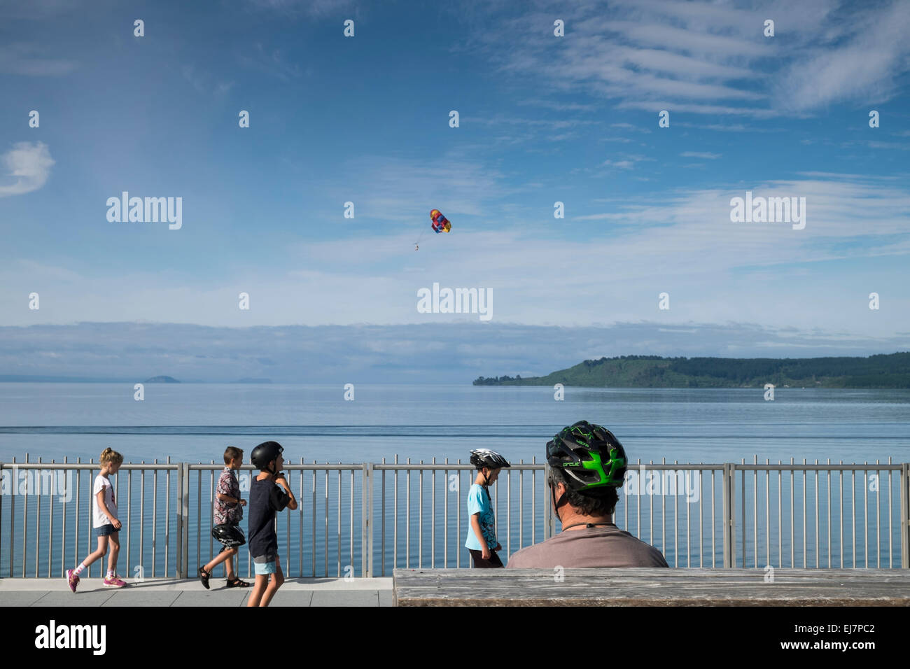 Mann mit Kindern tragen Schutzhelme Zyklus entlang der Gehweg neben Lake Taupo, Neuseeland. Stockfoto
