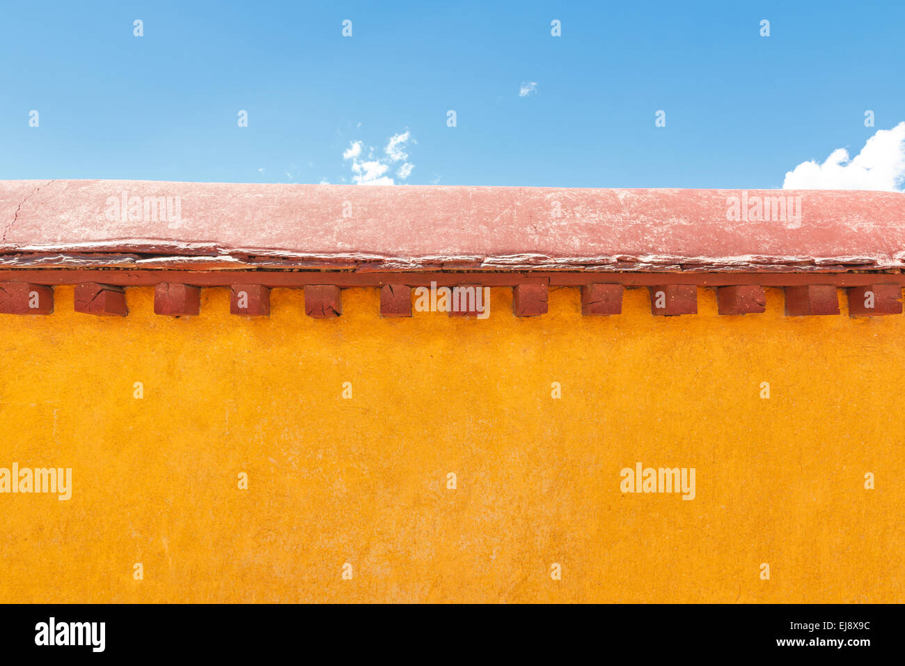 Gelbe Wand gegen blauen Himmel und ein paar kleine Wolken am Jokhang Tempel in Lhasa, Tibet Stockfoto