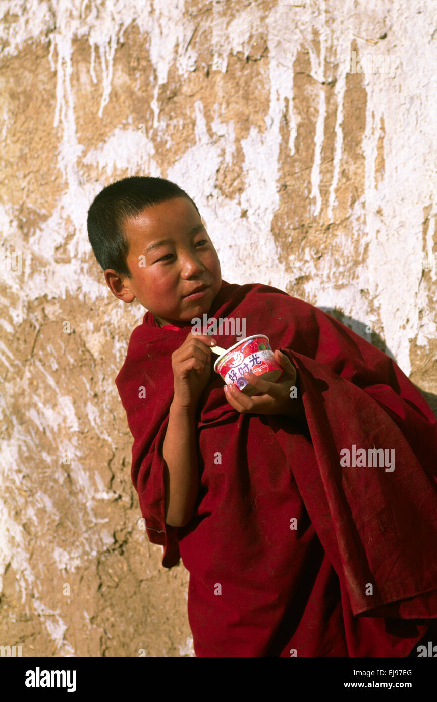 China, Tibet, Provinz Qinghai, Tongren (Repkong), Kloster Wutun Si, tibetischer Neujahrstag, Kindermönch isst Eis Stockfoto