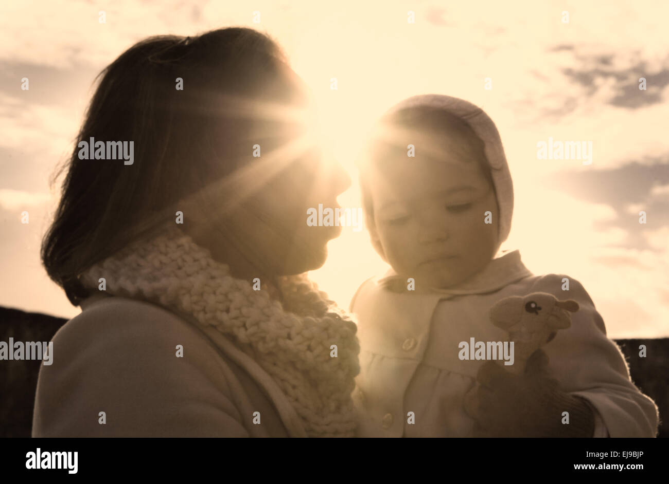 Mutter und Baby Mädchen zwischen einen Lichtstrahl der Wintersonne Stockfoto