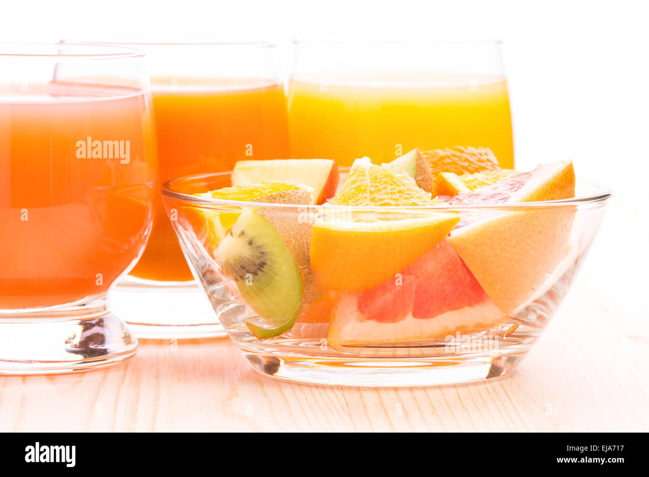 Salat von frischen Früchten in Glasschale mit verschiedenen Saft auf weißem Hintergrund. Gesunde Vitamine Essen Hintergrund Stockfoto