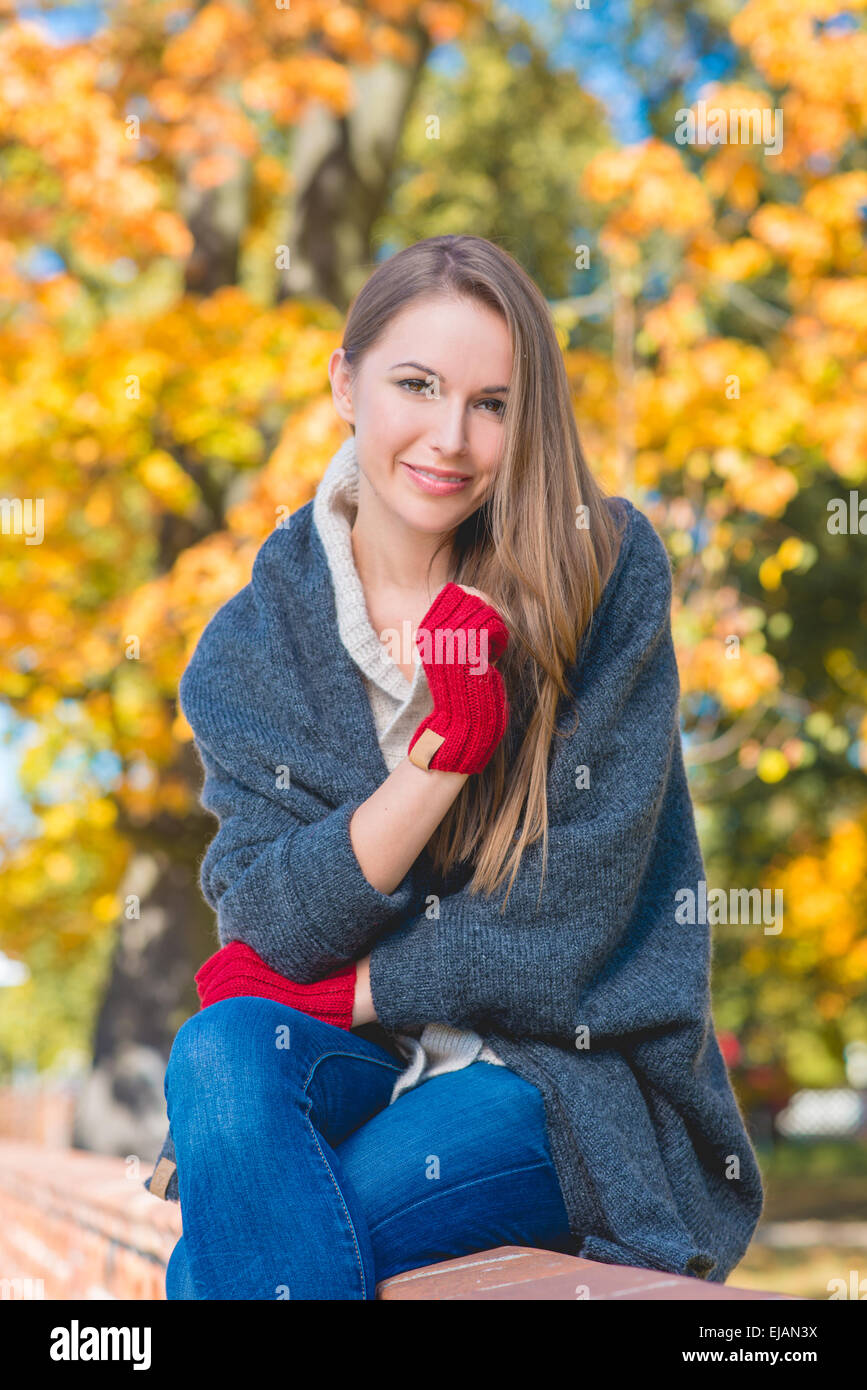 Trendige junge Frau auf einer Mauer sitzend Stockfoto