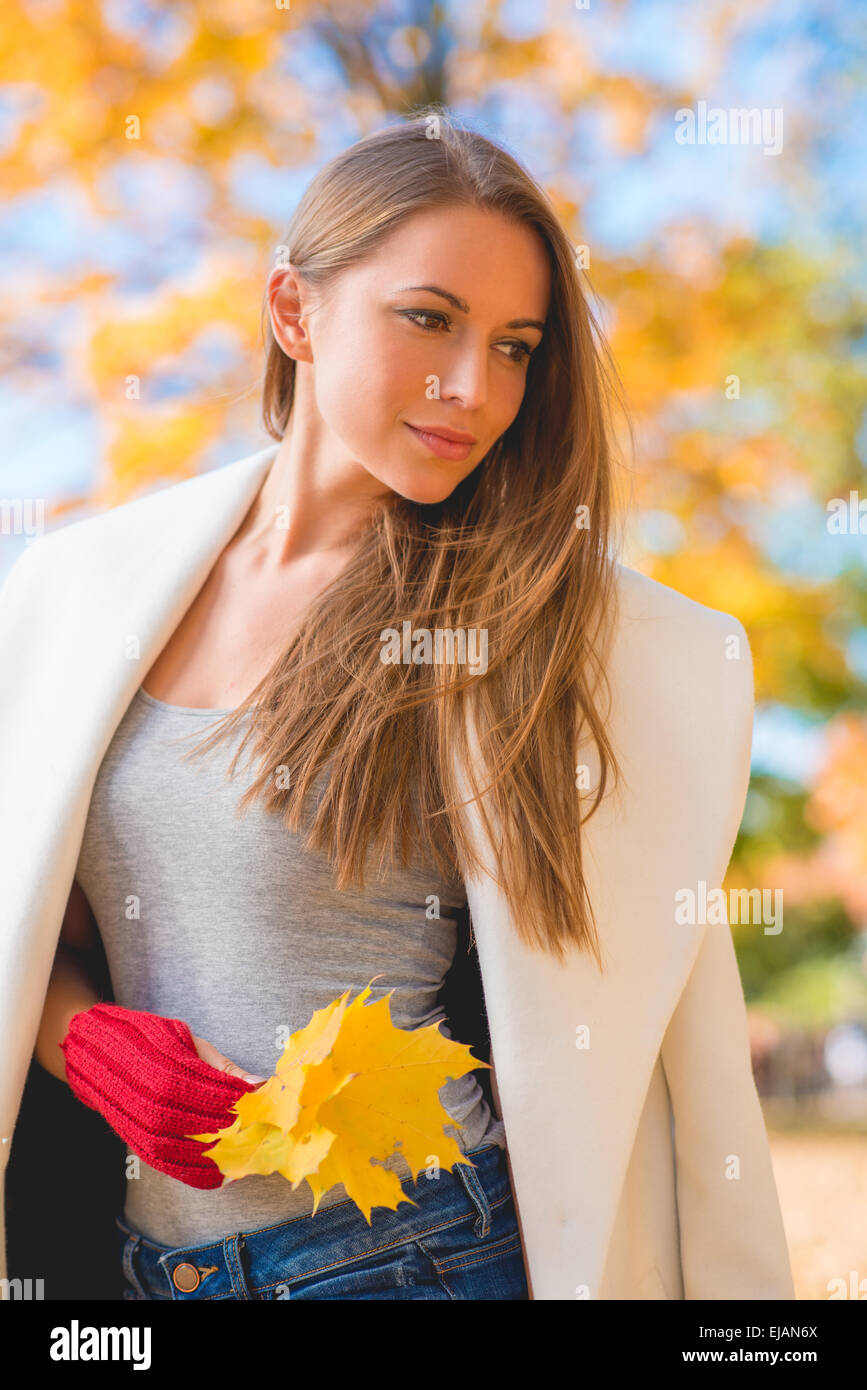 Nachdenkliche junge Frau mit Herbstlaub Stockfoto