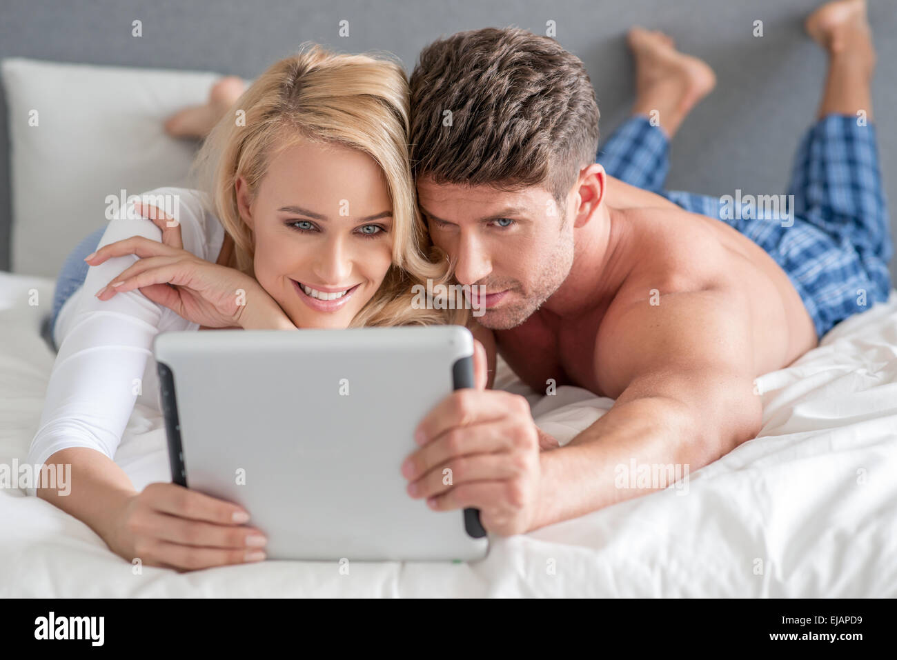 Junges Paar einen Tablet im Bett lesen Stockfoto
