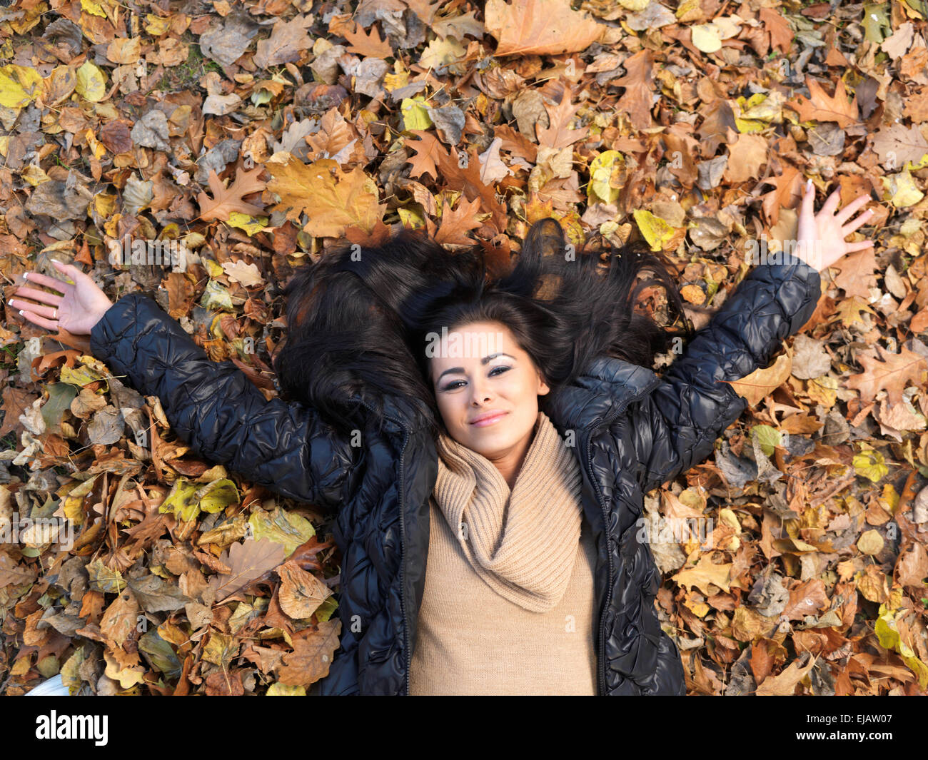 Frau auf dem Rücken liegend im Herbst Blätter Stockfoto