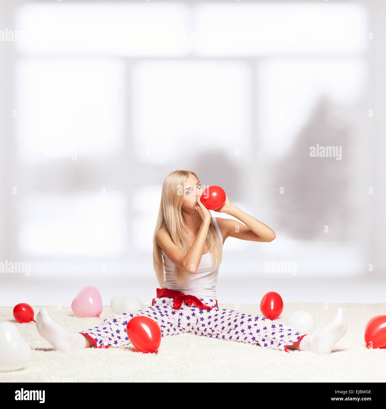 Blonde Frau aufblasen Luftballons Stockfoto