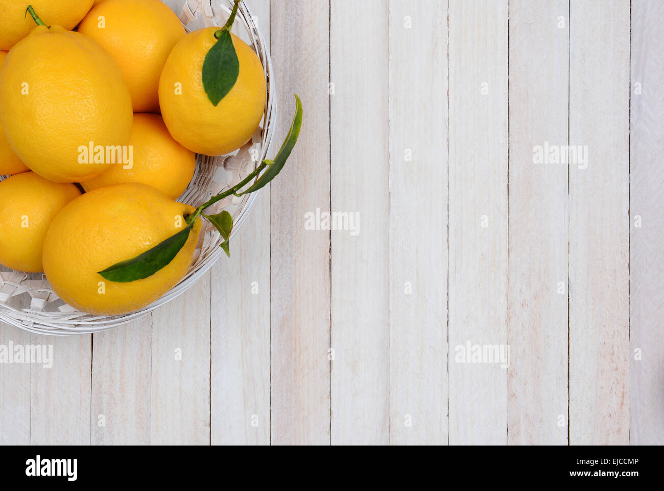 Hohen Winkel Schuss einen Korb mit frisch gepflückten Zitronen in der Ecke des Rahmens. Querformat mit Textfreiraum. Stockfoto