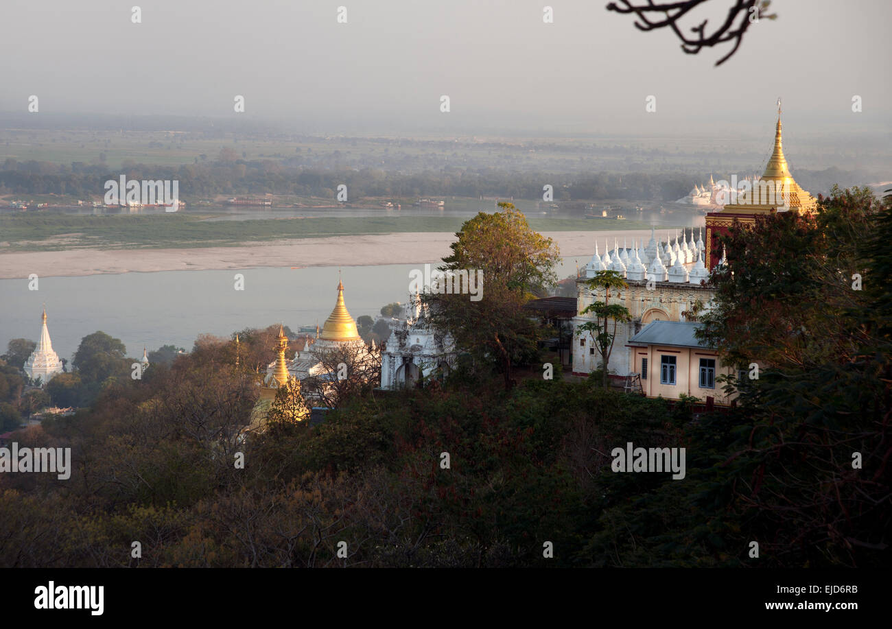 Blick auf goldene buddhistische Tempel, die im Sonnenuntergang auf dem Sagaing-Hügel über dem Fluss Ayeyarwady in der Nähe des Mandalay Myanmar (Birma) glühen Stockfoto