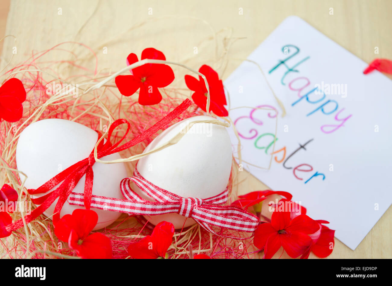 Weißes Ei in einem Nest mit Blumen und eine Karte "Frohe Ostern" Stockfoto