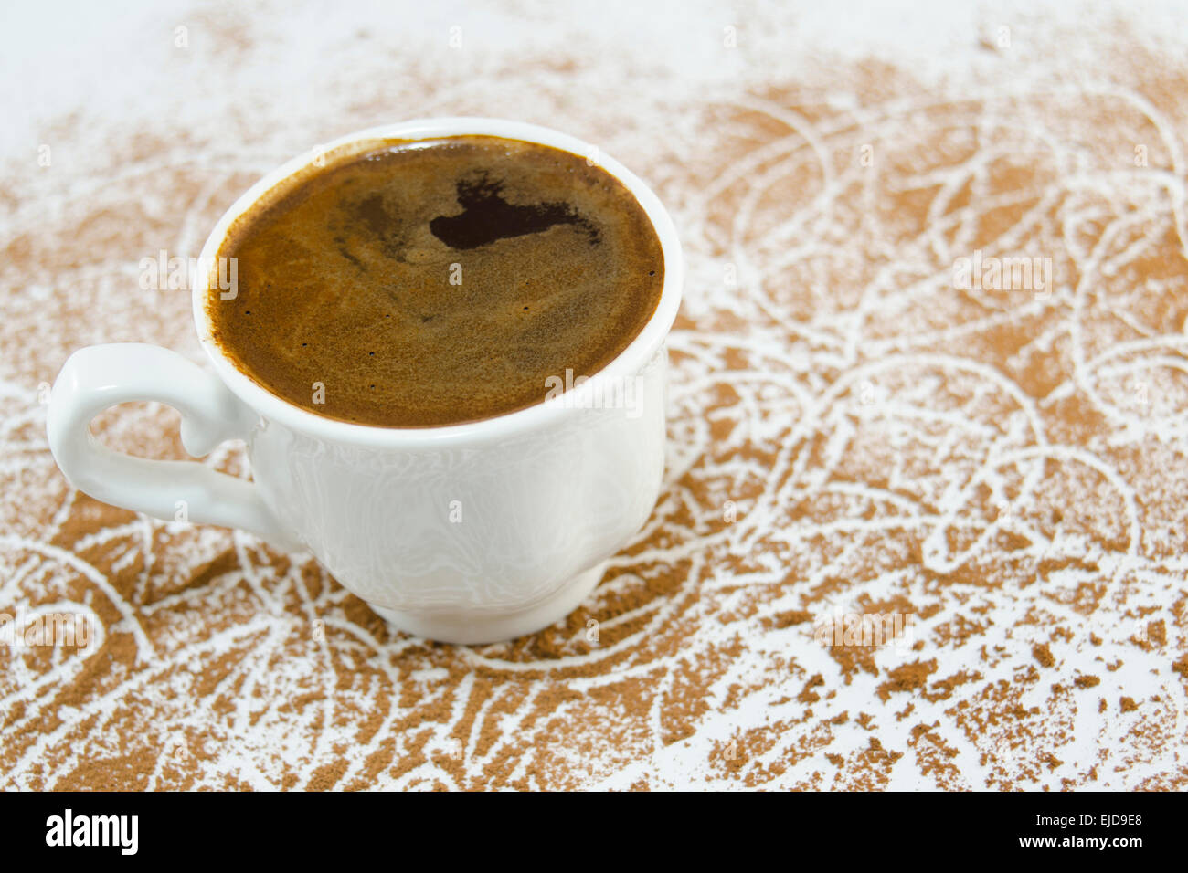 Tasse Kaffee auf einem weißen Tisch gedeckt mit geerdeten Kaffee Stockfoto