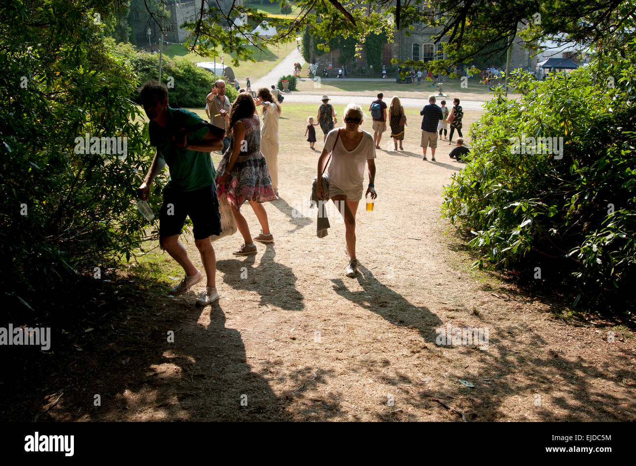 Festivalbesucher Silhouette gegen die Sonne Fuß durch die Bäume auf den Port Eliot Festival St deutschen Cornwall UK Stockfoto