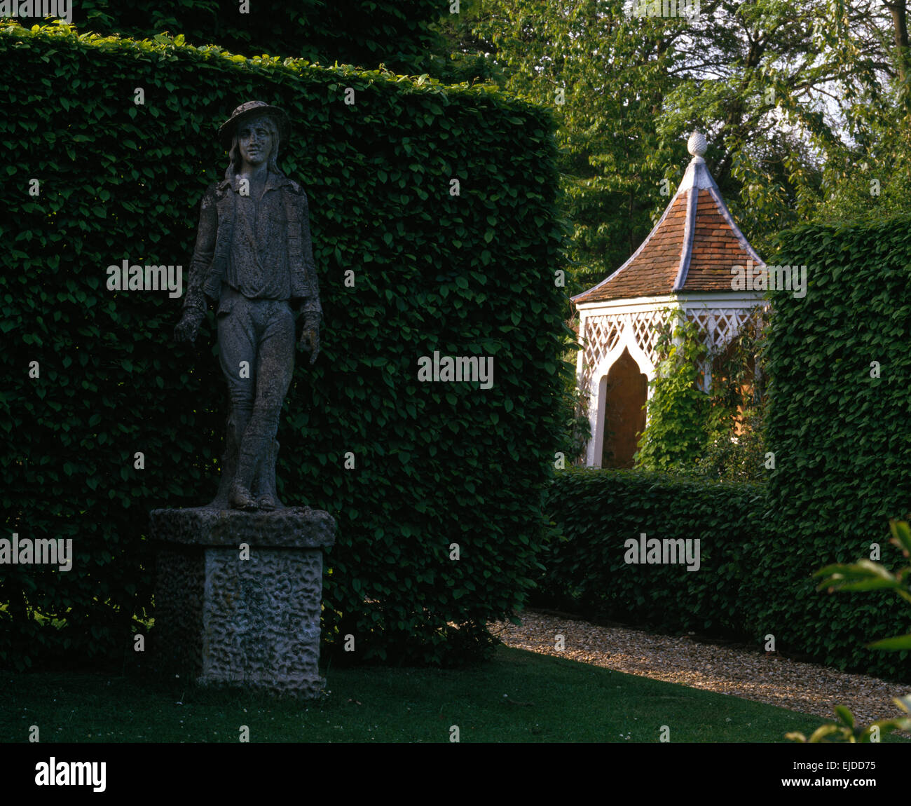 Steinstatue auf Sockel gegen abgeschnittene Buche Hecke im großen Bauerngarten mit Ziegeldach arbor Stockfoto