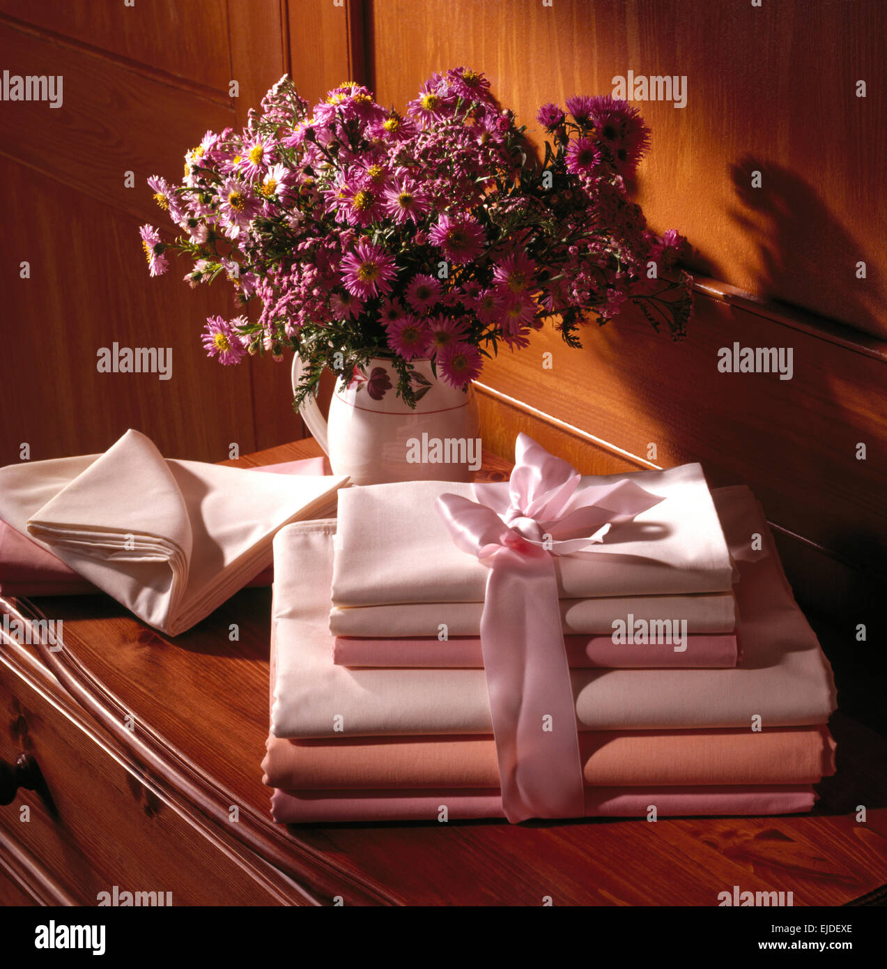 Nahaufnahme von Haufen von Falzbogen auf Brust mit Vase mit lila Astern Stockfoto