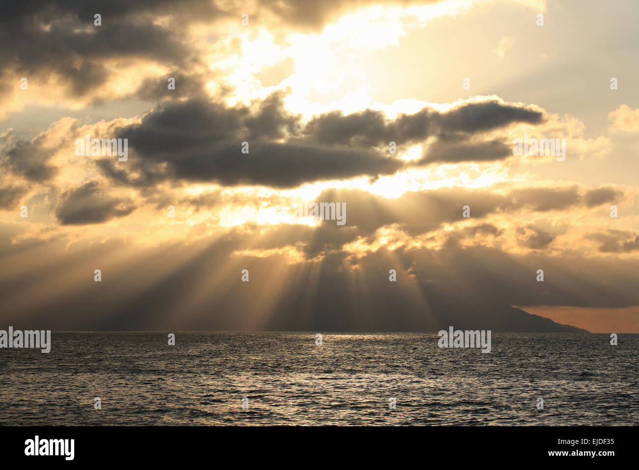 Sonnenuntergang über dem Ozean, Sonnenstrahlen fallen in das Wasser und Schichten von Wolken. Stockfoto