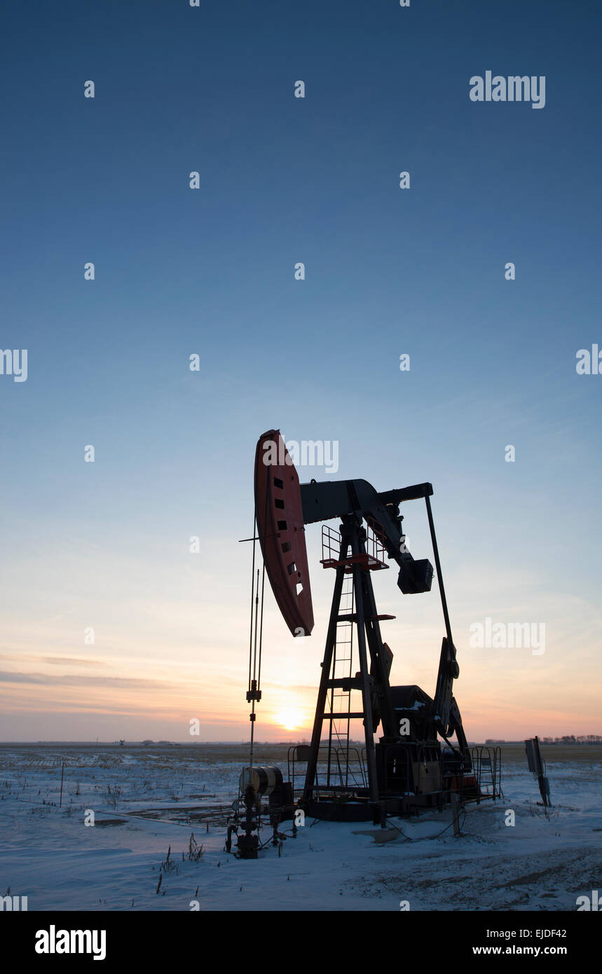 Ein Öl-Bohr-Rig und Bohrschwengels auf einer flachen Ebene in den kanadischen Ölfeldern bei Sonnenuntergang. Stockfoto