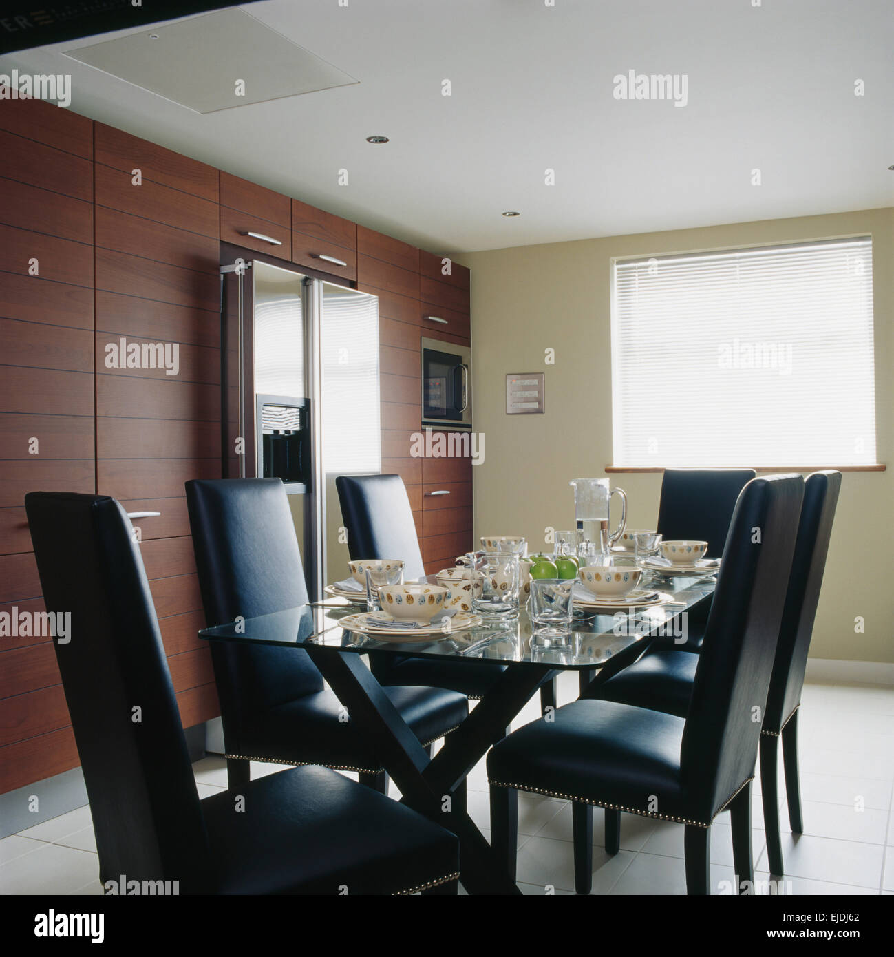 Schwarzen Ledersesseln am Glas gekrönt Esstisch zum Abendessen im Speisesaal der modernen Küche Stockfoto