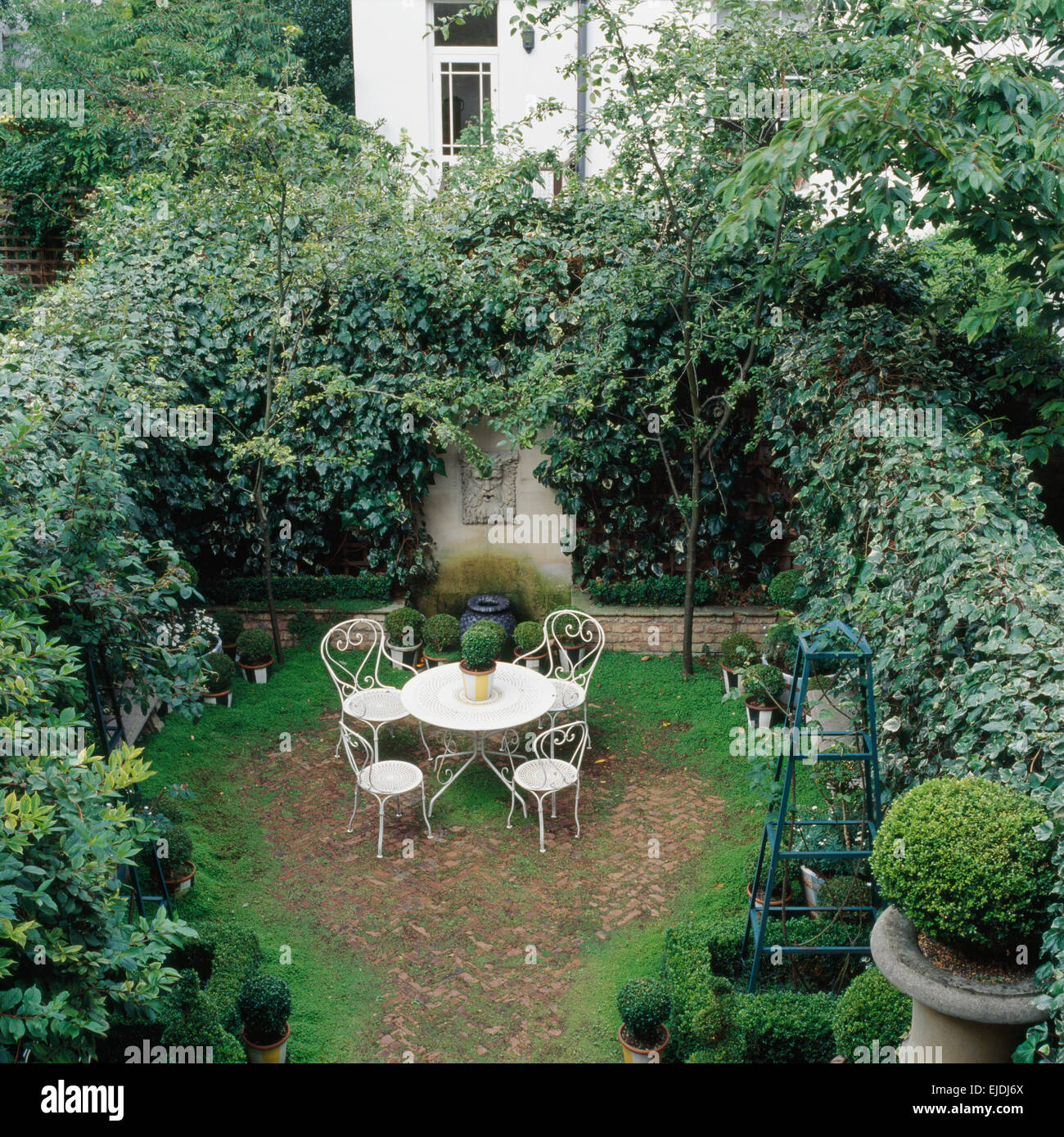 Vogelperspektive des weißen schmiedeeisernen Stühlen und Tisch im Stadthaus  Garten mit Efeu bedeckt Wände Stockfotografie - Alamy