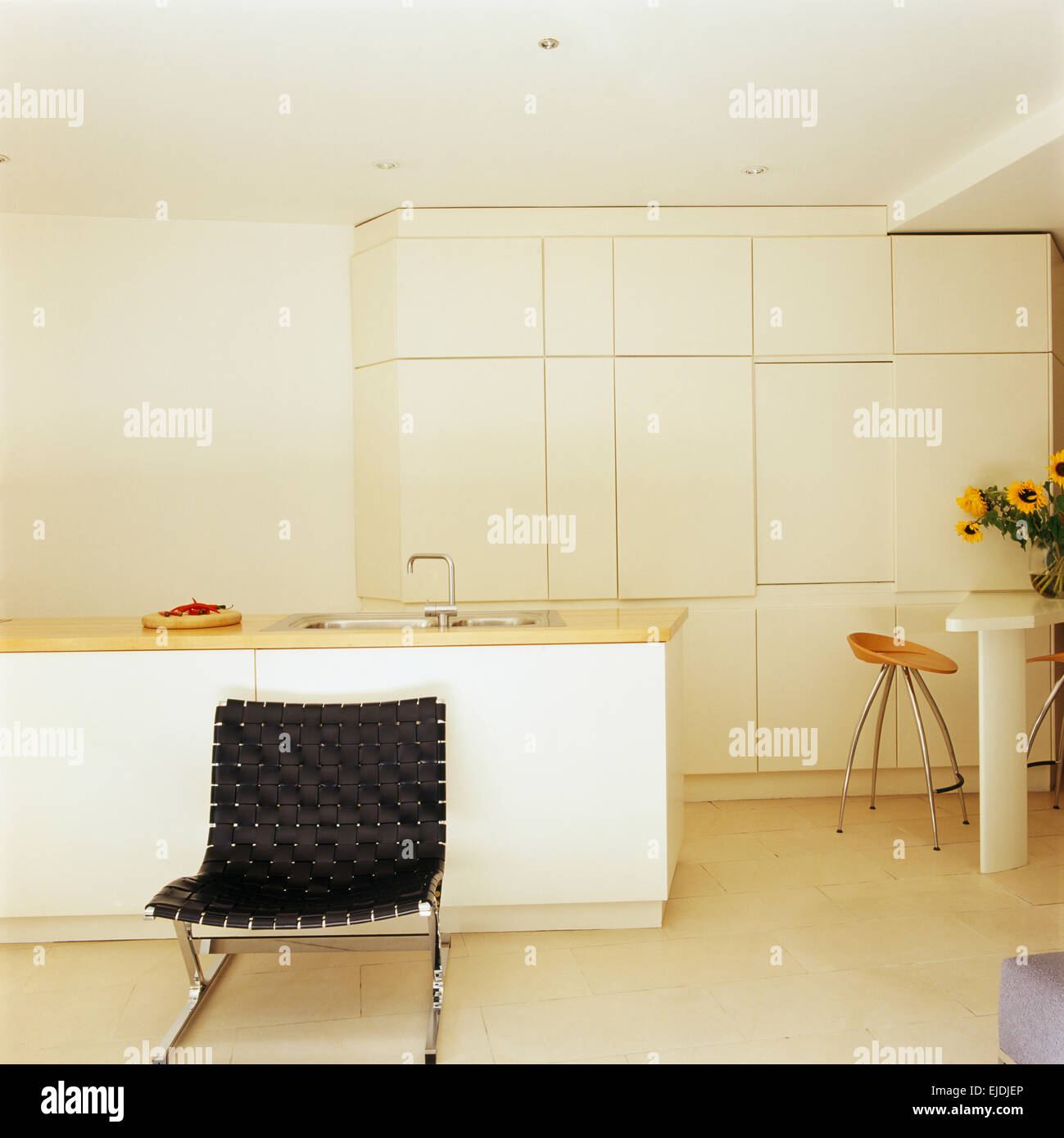 Schwarzen geflochtenen Leder und Chrom Stuhl in modernen weißen minimalistische Küche mit Wand optimierte Lagerung Schränke Stockfoto