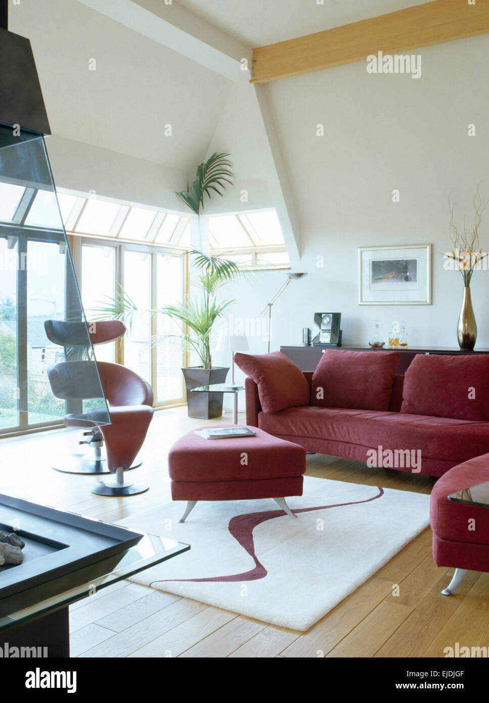 Tief rosa Sofa und Ottomane in modernen offenen Wohnraum mit abstrakten gemusterten Teppich Stockfoto