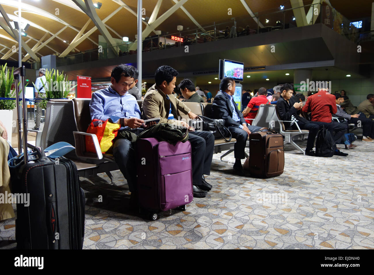 Reisende mit Gepäck warten in der Lounge des internationalen Flughafen Pudong in Shanghai, China Stockfoto