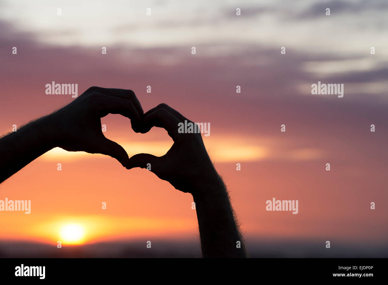 Herz Hände Geste bei Sonnenaufgang. Silhouette Stockfoto