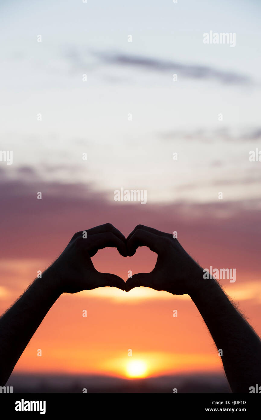 Herz Hände Geste bei Sonnenaufgang. Silhouette Stockfoto