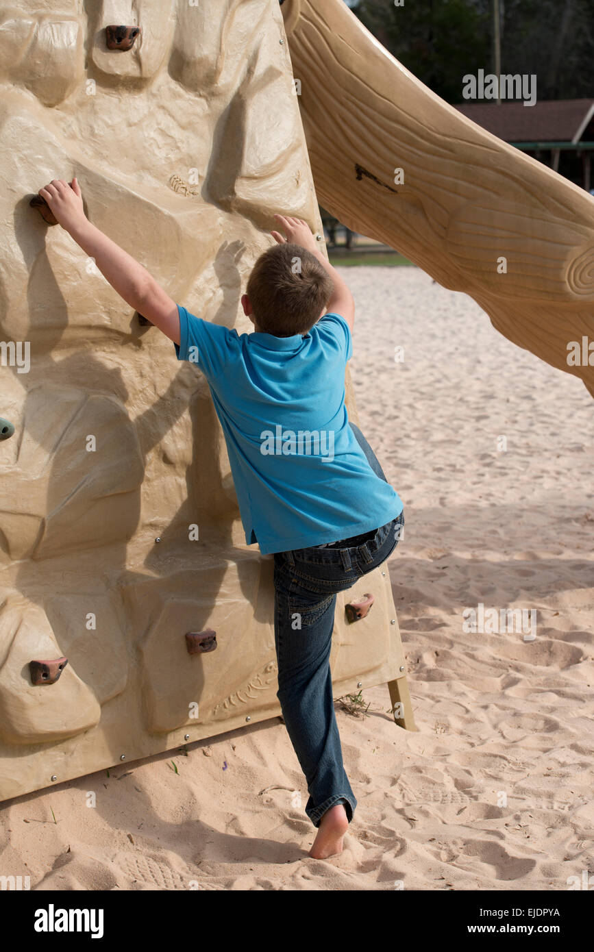 Acht Jahre alter Junge Rock Kletterwand am Park Spielplatz Stockfoto