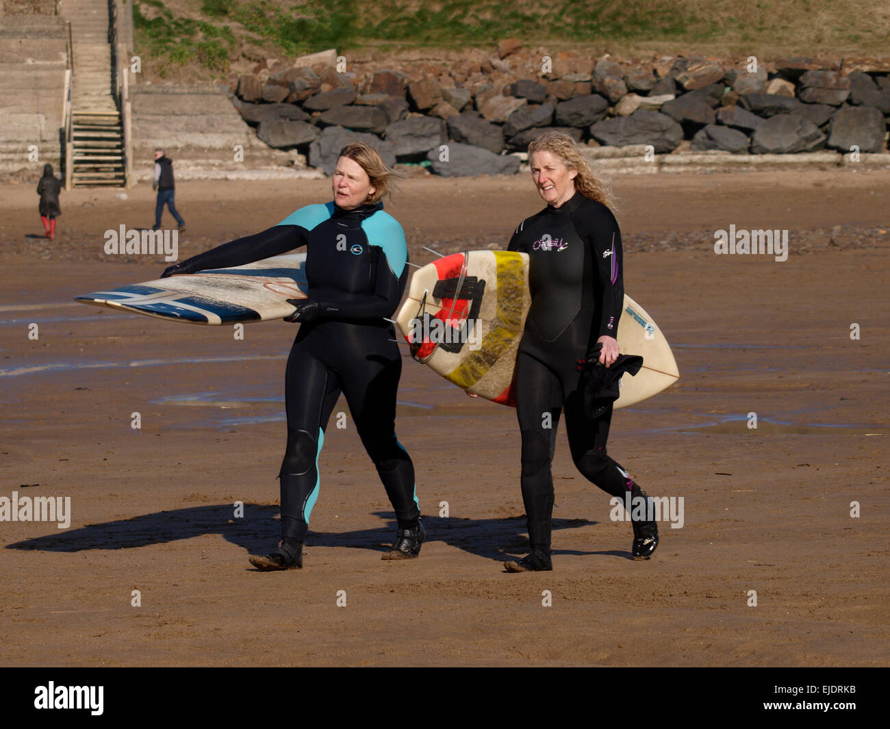 Zwei Surferinnen der mittleren Alters, die hinunter zum Strand tragen Surfbretter, Bude, Cornwall, UK Stockfoto