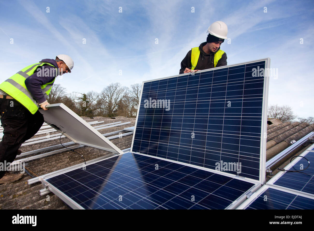 Andy Tyrrell und Jake Beautyman installieren Sonnenkollektoren auf dem Dach der Scheune auf Grange Farm nahe Balcombe. Die Installation ist Teil einer Stockfoto