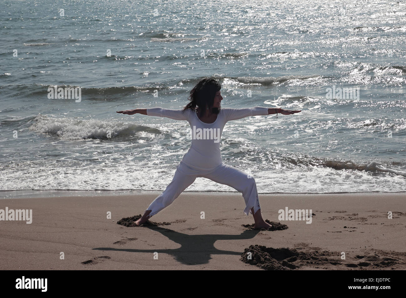 Frau üben Virabhadrasana Pose auf einem Ufer Stockfoto