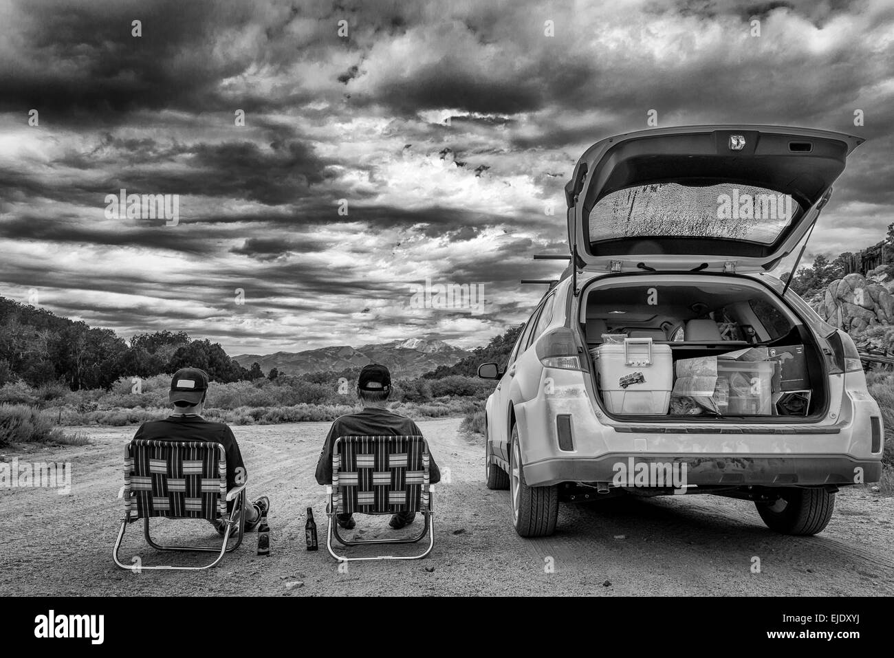 Zwei Männer sitzen neben einem Subaru Outback in schwarz / weiß Stockfoto