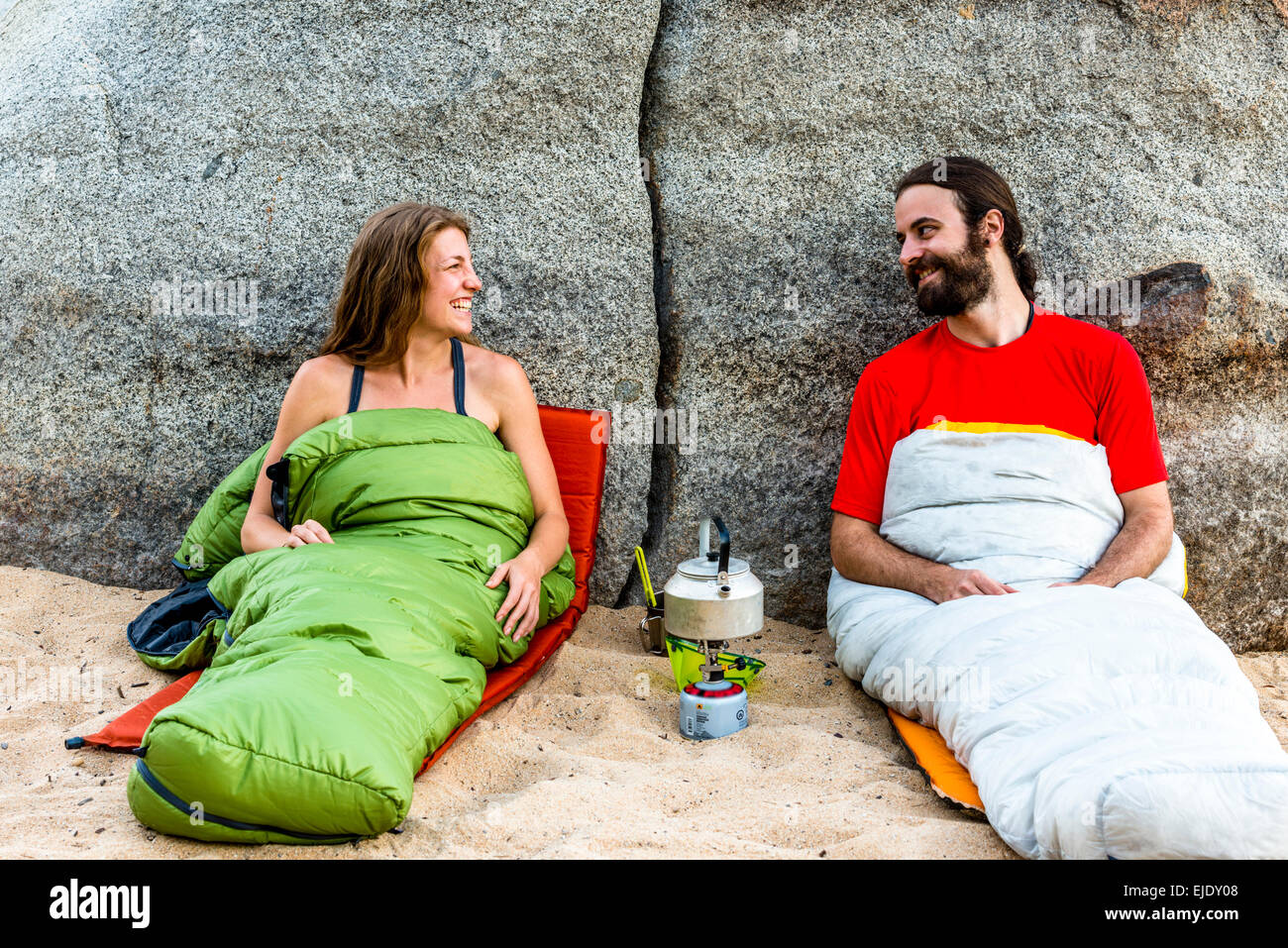 Mann und Frau am Strand in Schlafsäcke lachen Stockfoto