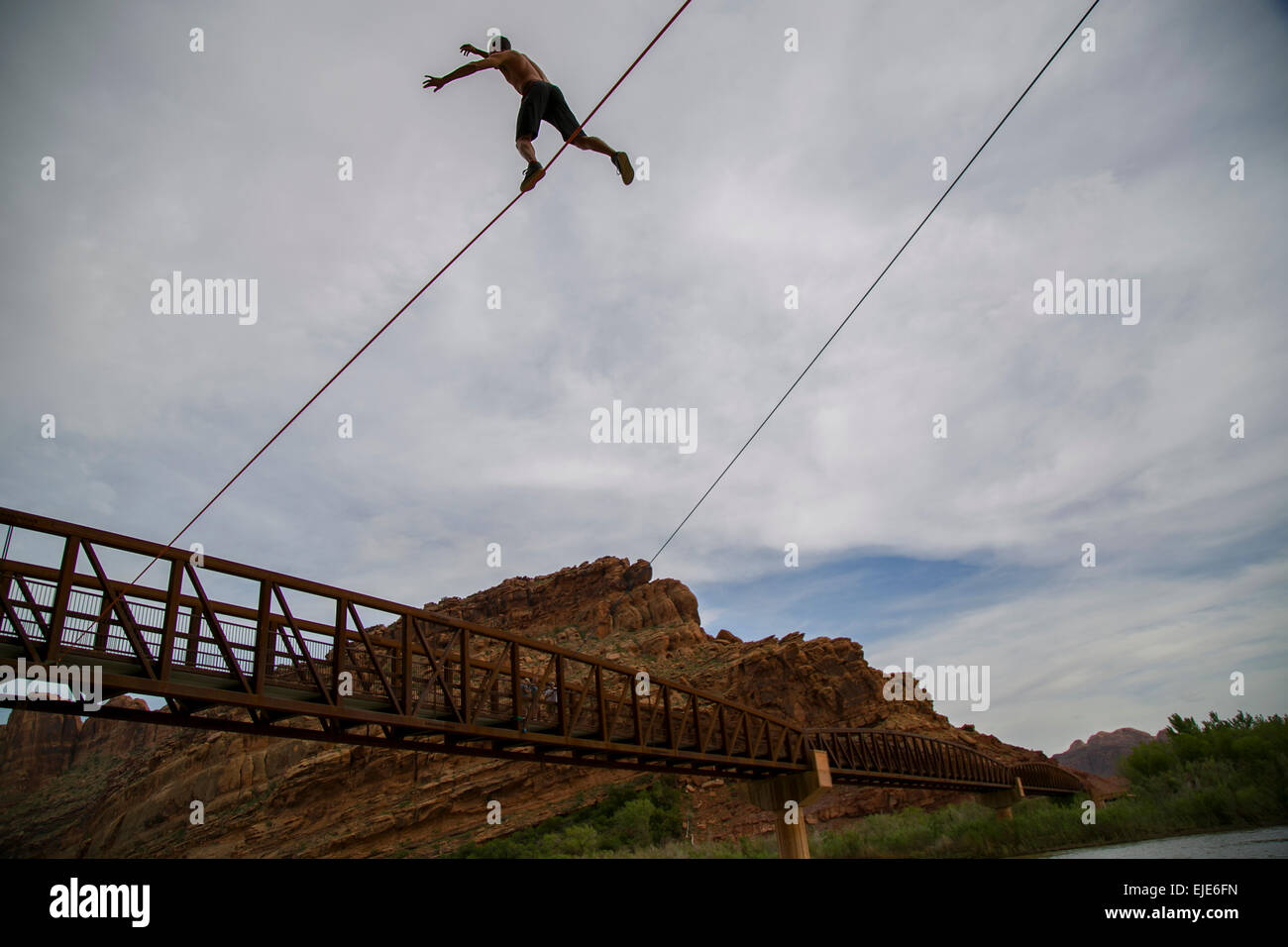 Ein junger Mann freie Soli eine Highline über einen Fluss in Moab, UT Stockfoto