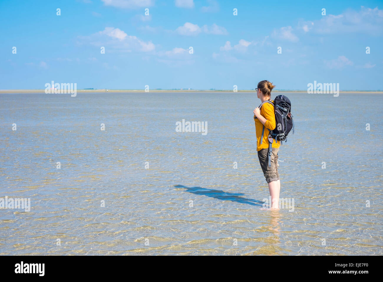 Junge Frau, die zu Fuß durch das Wattenmeer bei Ebbe (Wattenmeer) Stockfoto