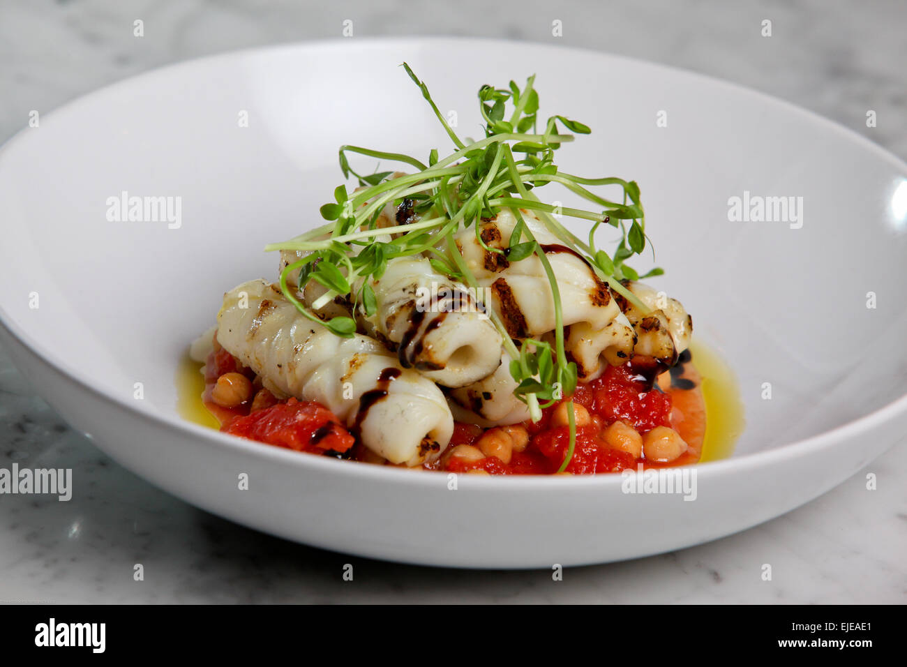 Gegrillte Calamari mit einer Tomate und Küken Erbse Soße, beträufelt mit Balsamico-Essig Stockfoto