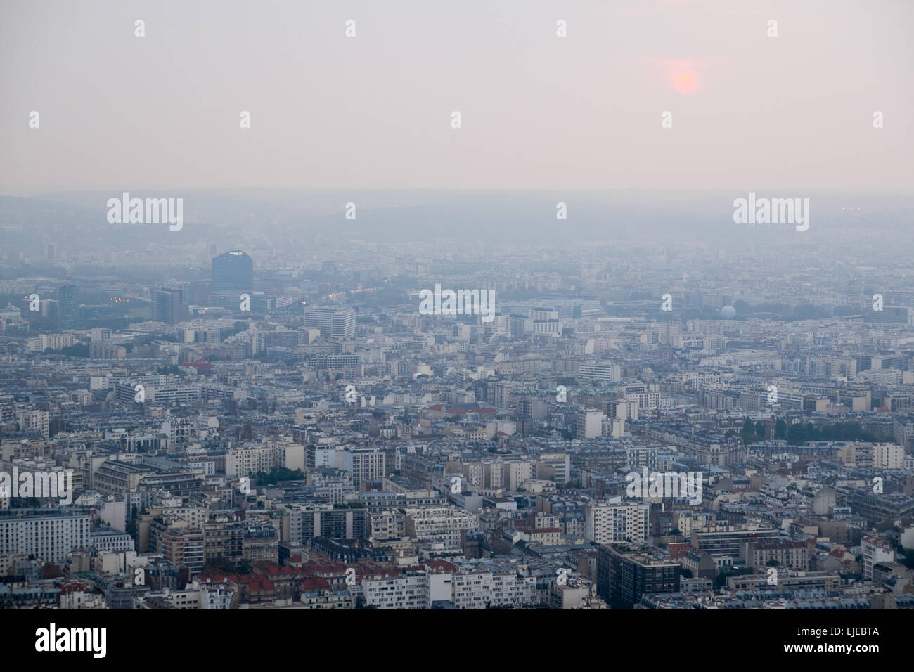 Eine dunstige Sonne sinkt auf den Horizont, wie die Stadt Paris unten streckt. Stockfoto