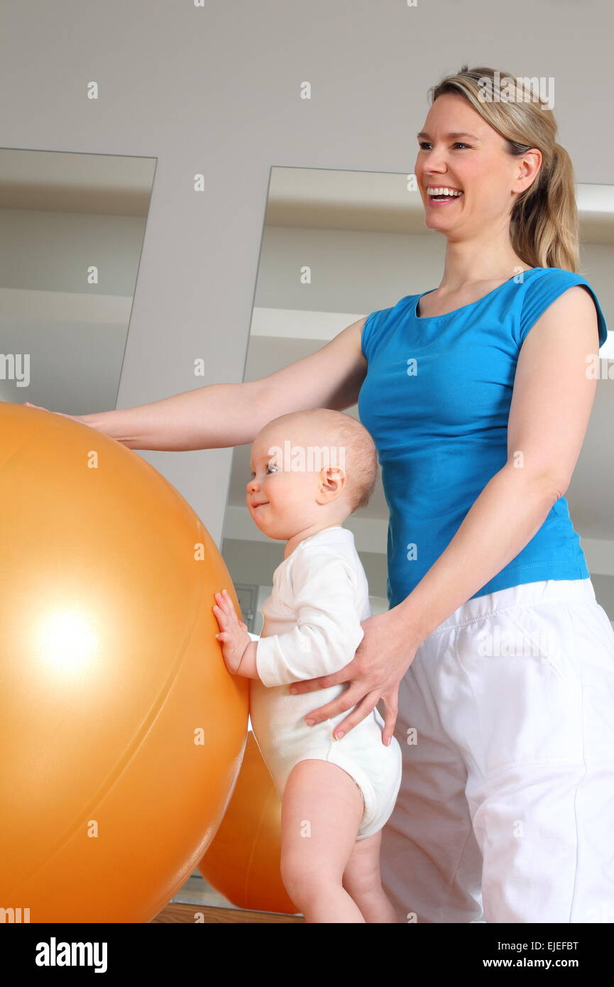 A Baby stehen bei Physiotherapie neben einem Fitness-Ball Stockfoto