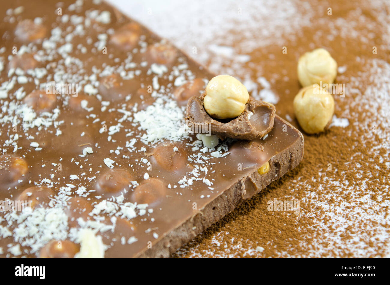 Ganzen Nüssen Schokolade auf einem Tisch mit Kakao und weißer Schokolade besprüht Stockfoto
