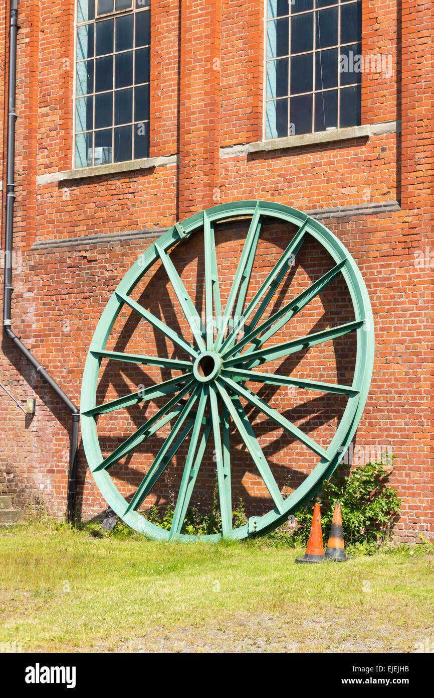 Eine große Kopfbedeckung Riemenscheibe für das Zechenhaus gewundenen Gang, lehnte sich gegen das Maschinenhaus Astley grünes Zeche-Museum. Stockfoto