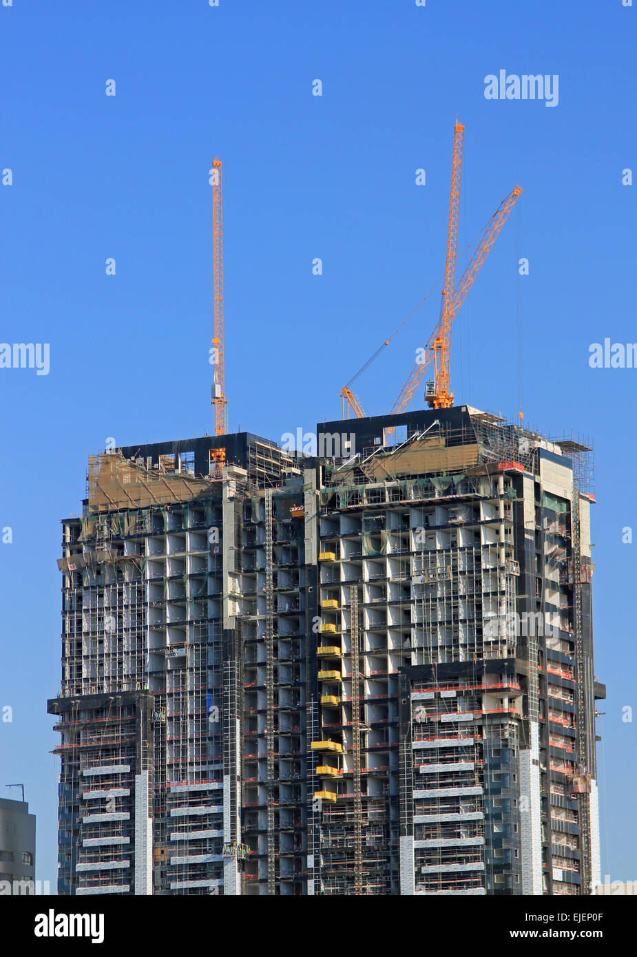 Gebäude im Bau mit Kränen auf dem Dach, Gerüste und Baumaterialien, die als Symbol für Bau und Wachstum Stockfoto